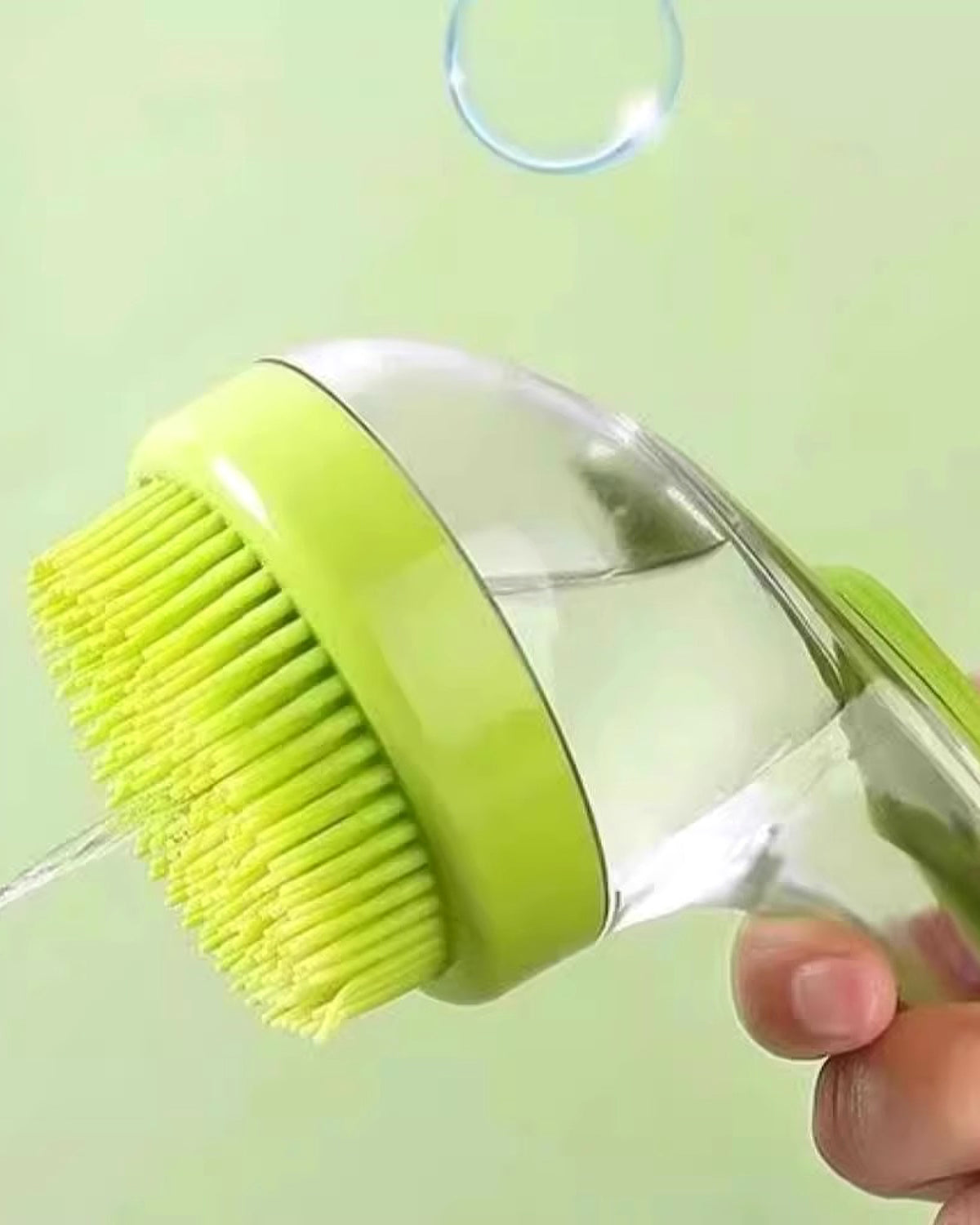 The bath brush held in one hand with water flowing through it